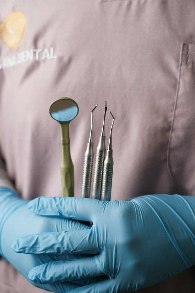 A person in blue gloves holding a set of dental instruments